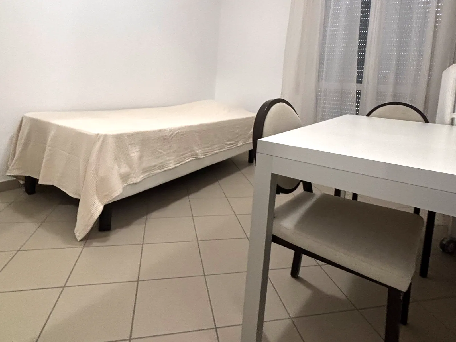 Una camera singola con letto e scrivania